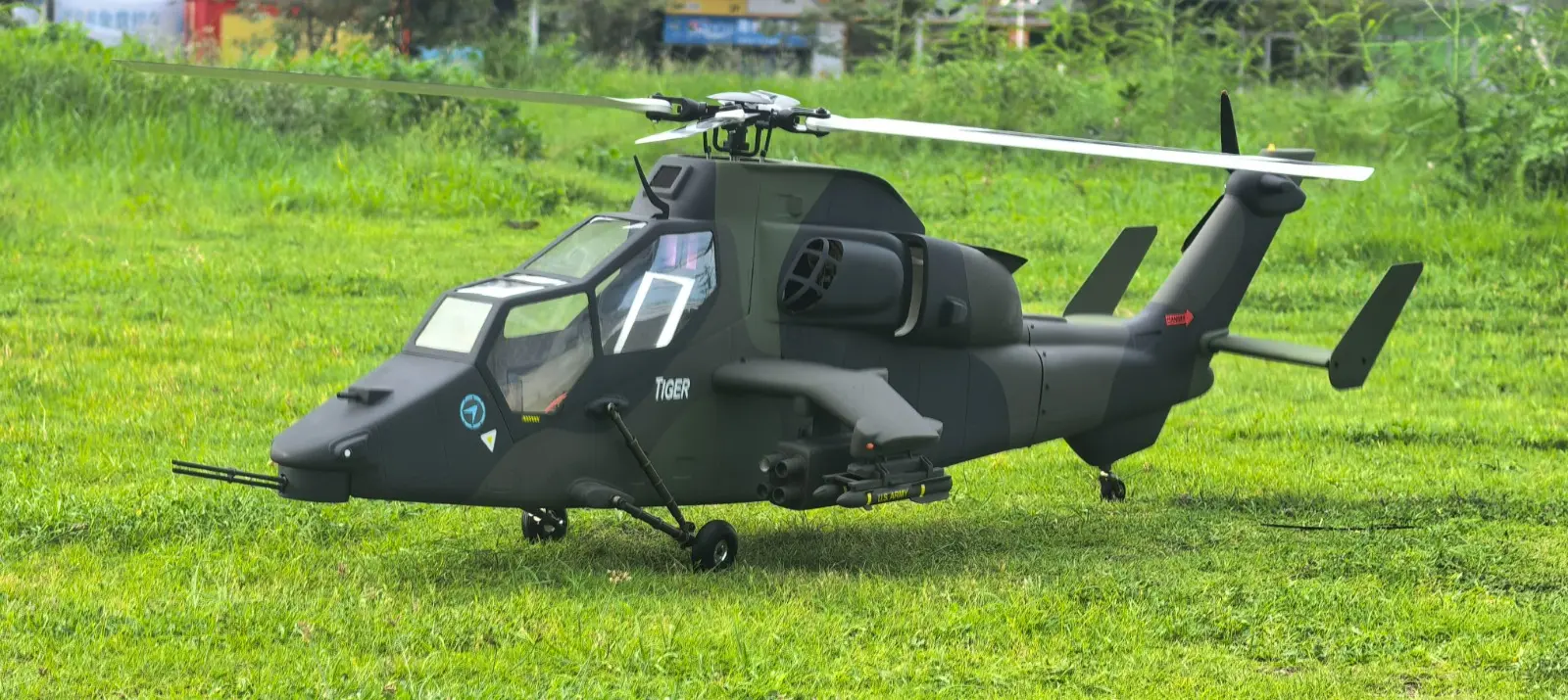 FLISHRC Tiger 700-size scale RC helicopter in green and black camouflage, side profile on grass