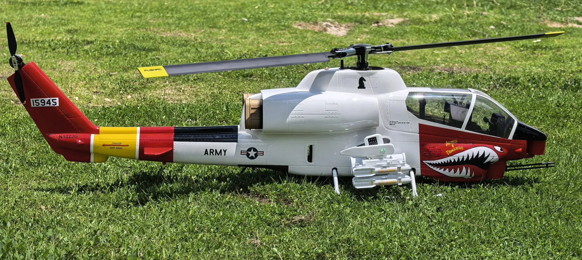 Low-angle side view of the FLISHRC AH-1 Cobra 500-class scale RC helicopter in white and red